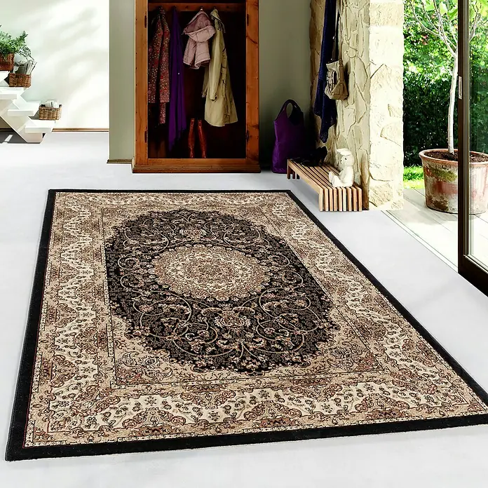 Kurzflorteppich Kashmir 2606Schwarz, 340 x 240 cm, 100% Polypropylen - Ein detailreicher Teppich mit einem klassischen orientalischen Muster in Beige- und Schwarztönen liegt in einem hellen Raum.