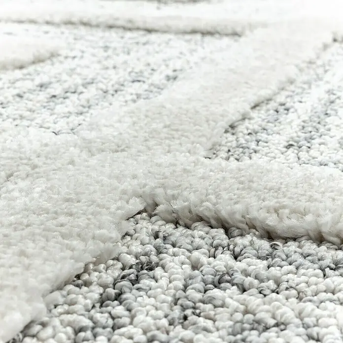 Hochflorteppich Pisa 4707Grau, 150 x 80 cm, 100% Polypropylen - Nahaufnahme eines weißen Teppichs mit erhabenem Muster, der Textur und Komfort hervorhebt. Ideal für jeden Raum, der Wärme benötigt.