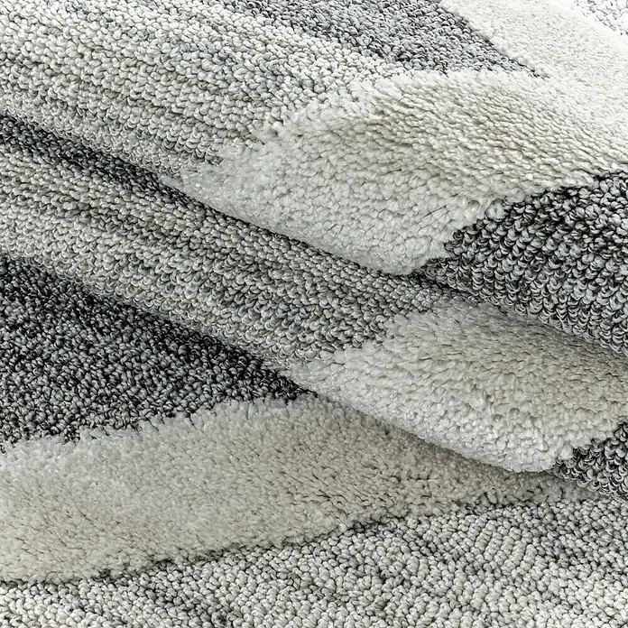 Hochflorteppich Pisa 4709 - Grau, 290 x 200 cm, 100% Polypropylen - Nahaufnahme eines weichen, gestreiften Teppichs in Grau- und Weißtönen, der eine gemütliche Textur zeigt.