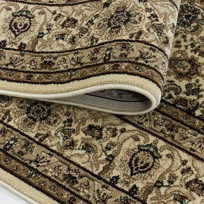 Kurzflorteppich Kashmir 2602Beige, 150 x 80 cm, 100% Polypropylen - Nahaufnahme eines beigefarbenen Teppichs mit braunen Ornamenten und gerollten Kanten, der seine Textur und sein Design hervorhebt.