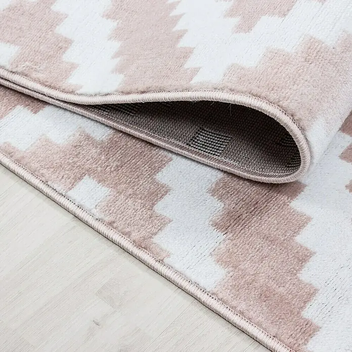 Kurzflorteppich Plus 8005Pink, 290 x 200 cm, 100 % Polypropylen - Nahaufnahme eines Teppichs mit geometrischem Muster in Rosa und Weiß, der eine gemütliche und stilvolle Atmosphäre ausstrahlt.