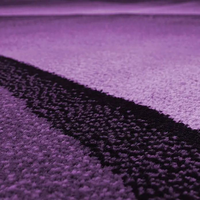 Kurzflorteppich Plus 8010 - Lila, 200 x 140 cm, 100 % Polypropylen - Nahaufnahme eines lilafarbenen Teppichs mit einem abstrakten schwarzen Muster, das eine luxuriöse Textur und ein modernes Design zeigt.