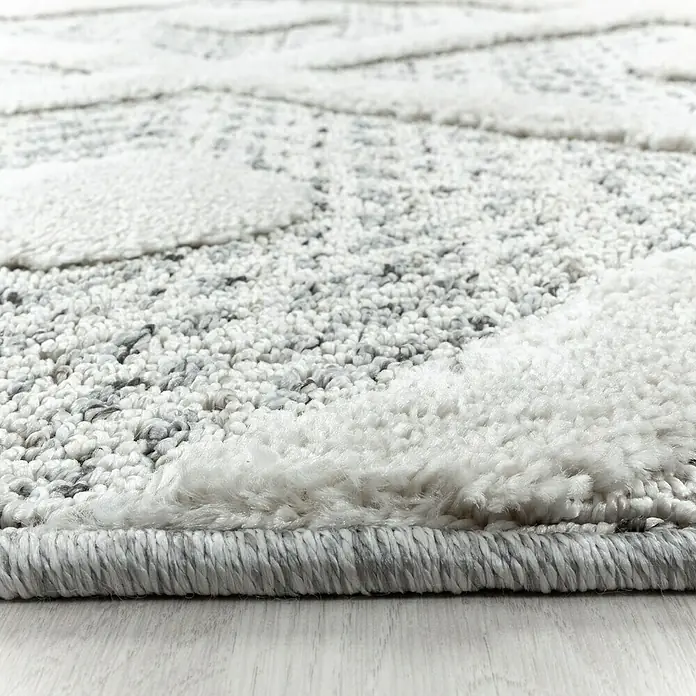 Hochflorteppich Pisa 4707 - Grau, Durchmesser: 80 cm, 100% Polypropylen - Nahaufnahme eines Teppichs mit abstraktem Muster in Weiß- und Grautönen, der eine weiche Textur und einen modernen Look zeigt.