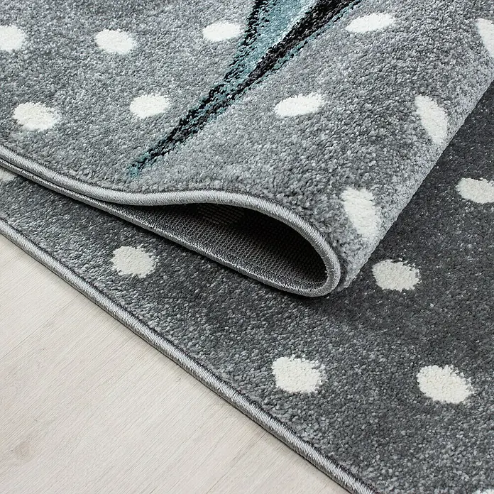 Kinderteppich Kids 0580Blau, 150 x 80 cm, 100 % Polypropylen - Ein grauer Teppich mit weißen Punkten ist zusammengerollt und zeigt seine Unterseite.