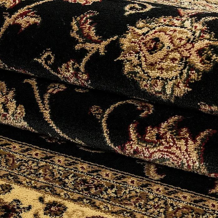 Kurzflorteppich Orient-Optik Marrakesh 0210 - Schwarz, 290 x 200 cm, 100% Polypropylen - Nahaufnahme eines kunstvoll gemusterten Teppichs mit floralen Ornamenten und verschlungenen Ranken in Schwarz-, Beige- und Rottönen.
