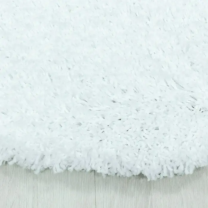 Hochflorteppich Sydney 3000Weiß, Durchmesser: 120 cm, 100% Polypropylen - Nahaufnahme eines flauschigen, weißen Teppichs, der sich sanft über einen hellen Holzboden legt und ein Gefühl von Komfort und Wärme vermittelt.