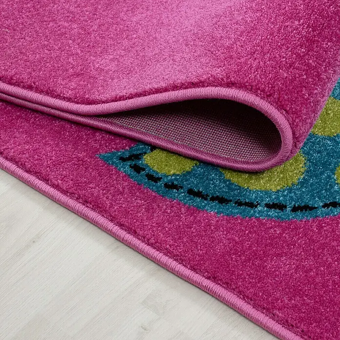 Kinderteppich Kids 0420 - Lila, 230 x 160 cm, 100% Polypropylen - Detailansicht eines pinkfarbenen Teppichs mit farbenfrohem Muster und umgeschlagenem Rand, der die Rückseite zeigt.