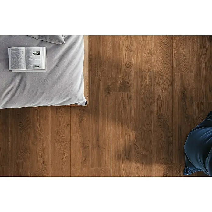 Atlas Concorde Solution Living Nature Feinsteinzeugfliese Twist Amber - 22,5 x 90 cm, Braun, Matt - Einladendes Schlafzimmer mit warmen Holzdielen, einem offenen Buch auf dem Bett und sanftem Tageslicht.