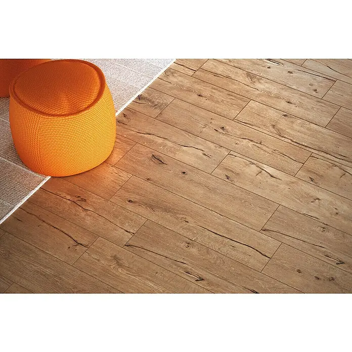 Atlas Concorde Solution Fable Feinsteinzeugfliese Honey - 22,5 x 90 cm, Braun, Matt - Nahaufnahme eines hellen Holzfußbodens mit einem orangefarbenen Pouf und einem Teppichstück. Das Holzdesign verleiht Wärme.