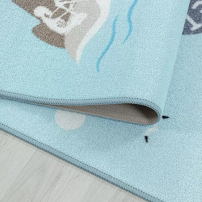 Kinderteppich Play 2908 - Blau, 230 x 160 cm, 100% Polyamide - Hellblauer, weich strukturierter Kinderteppich, teilweise aufgerollt, mit genähten Kanten und dezenten Tier-/Seefahrtsmustern.