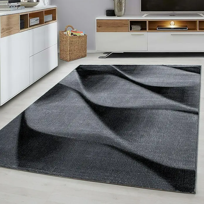 Kurzflorteppich Parma 9240 - Schwarz, 300 x 80 cm, 100% Polypropylen - Ein grauer Teppich mit einem abstrakten, wellenförmigen Muster liegt auf einem hellen Holzboden vor modernen Möbeln.