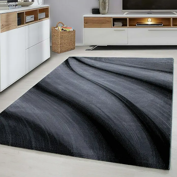 Kurzflorteppich Miami 6630 - Schwarz, 300 x 80 cm, 100% Polypropylen - Ein stilvoller, grauer Teppich mit einem abstrakten, wellenartigen Muster liegt in einem modern eingerichteten Wohnzimmer.