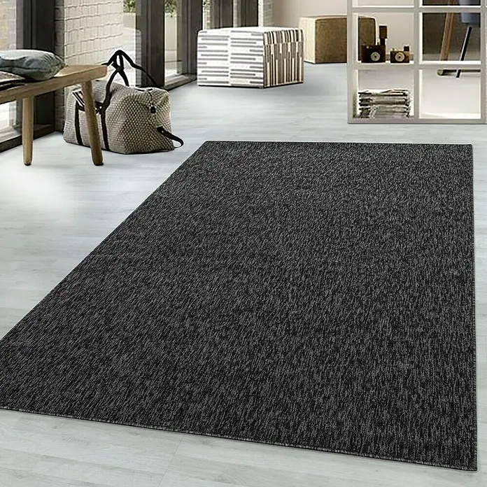 Flachgewebeteppich Nizza 1800 - Anthrazit, 100 x 60 cm, 100% Polypropylen - Ein dunkler Teppich mit feiner Textur liegt auf einem hellen Boden und verleiht dem Raum Wärme und Stil.