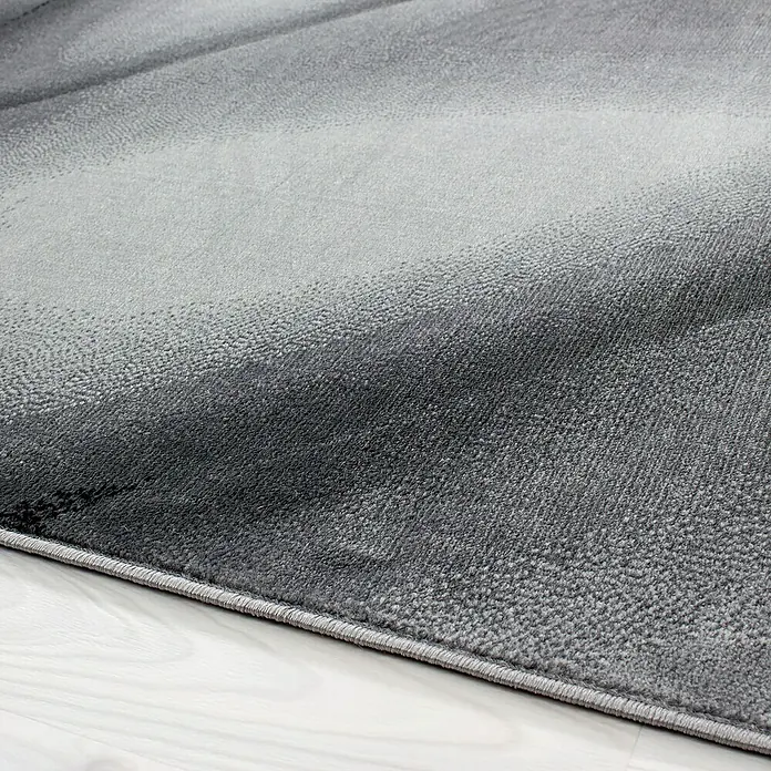 Kurzflorteppich Miami - Schwarz, 200 x 140 cm, 100 % Polypropylen - Nahaufnahme eines modernen grauen Teppichs mit subtilem Farbverlauf und feiner Textur auf hellem Holzboden.