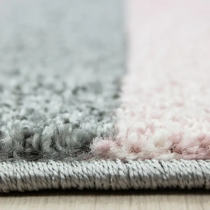 Kurzflorteppich Lucca 1810Pink, 290 x 200 cm, 100% Polypropylen - Nahaufnahme eines grauen und rosafarbenen Teppichs, der die weiche Textur und die Farbkontraste des Teppichs hervorhebt.
