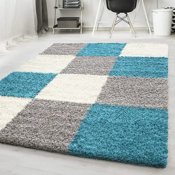 Hochflorteppich Life 1501 - Türkis, 290 x 200 cm, 100% Polypropylen - Ein flauschiger Teppich mit einem geometrischen Muster aus blauen, grauen und weißen Quadraten im Innenraum.