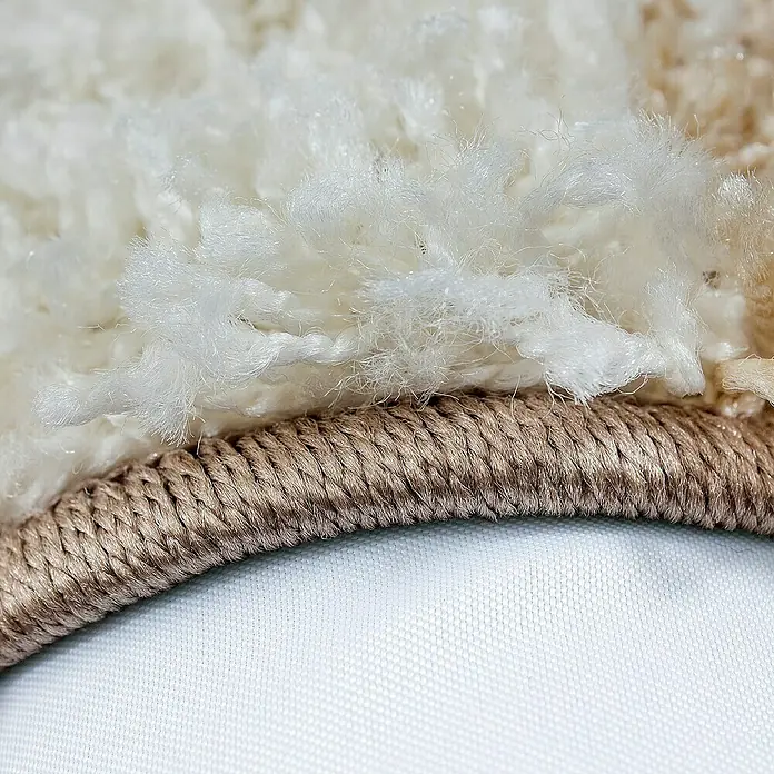 Hochflorteppich Life 1501Mocca, 150 x 80 cm, 100% Polypropylen - Detailaufnahme eines Teppichs mit cremefarbenem Flor und brauner Bordüre. Ein luxuriöses Detail, das Wärme und Textur in Ihr Zuhause bringt.
