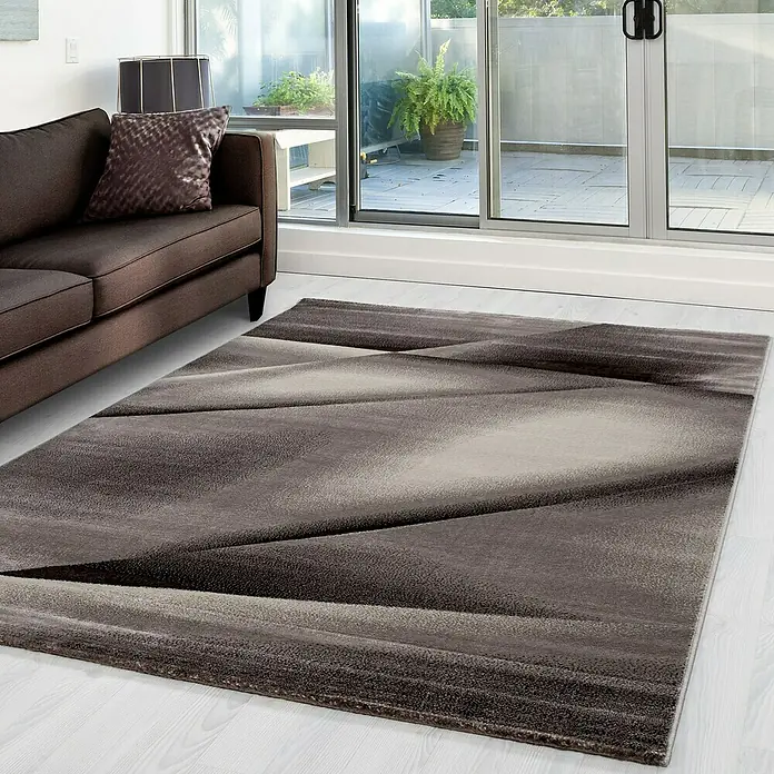 Kurzflorteppich Miami - Braun, 340 x 240 cm, 100 % Polypropylen - Ein modernes Wohnzimmer mit einem braunen Sofa und einem auffälligen, grauen Teppich mit geometrischem Muster.