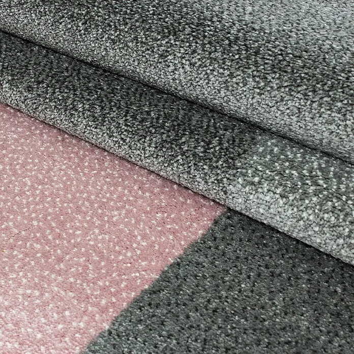 Kurzflorteppich Lucca 1810Pink, 290 x 200 cm, 100% Polypropylen - Detailansicht eines Teppichs mit grauem Flor und rosa Akzenten, der Textur und Design hervorhebt.\n