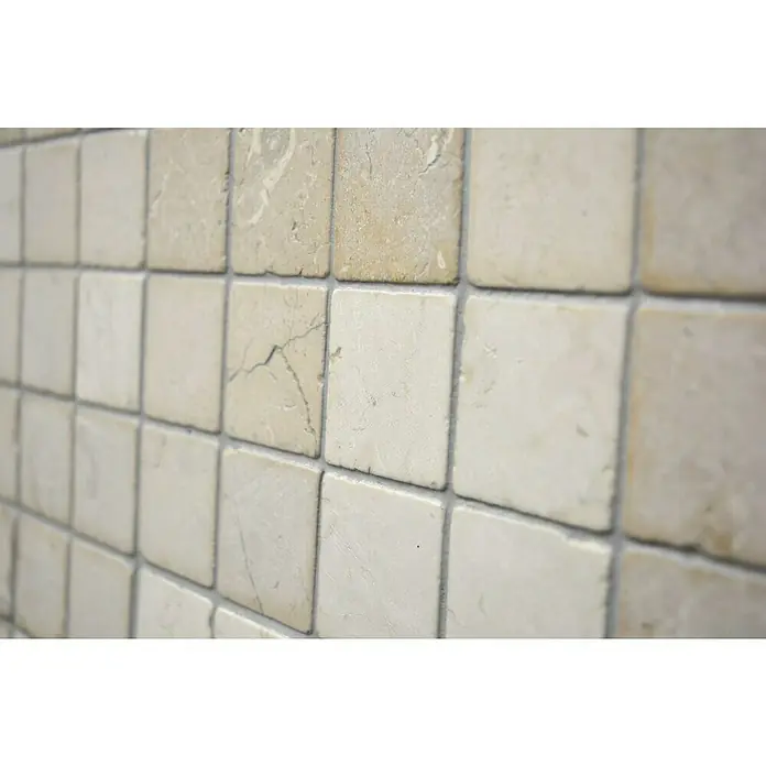 Mosaikfliese Quadrat Uni MOS TN48W - 30,5 x 30,5 cm, Cremeweiß, Matt - Nahaufnahme einer Wand mit quadratischen, beigen Fliesen mit leichter Marmorierung und grauen Fugen, die ein rustikales Flair verleihen.