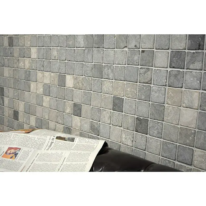 Mosaikfliese Quadrat Uni MOS TN48LG - 30,5 x 30,5 cm, Lichtgrau, Matt - Nahaufnahme einer Wand, die mit einem Mosaik aus grauen und beigen quadratischen Fliesen verziert ist, ergänzt durch eine Zeitung.