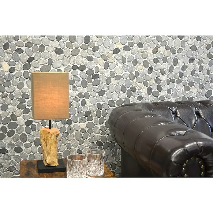 Mosaikfliese XKS INAS - 30,5 x 30,5 cm, Grau, Matt - Einrichtung mit Kieselmosaikwand, rustikaler Lampe auf Holztisch und Ledersofa. Die graue Wand harmoniert mit dem stilvollen Interieur.