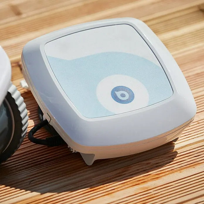 BWT Poolroboter B 100 - Netzbetrieben, Passend für: Pools bis 60 m², Filterleistung: 19.000 l/h - Nahaufnahme eines automatischen Poolreinigungsroboters. Das Gerät steht auf einem Holzdeck und verfügt über ein blaues Design auf der Oberseite.
