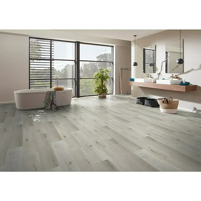 b!design Vinylboden SPC - Savannah Eiche, Landhausdiele, 1.220 x 181 x 3,5 mm - Helles Badezimmer mit einer freistehenden Badewanne, einem großen Fenster und einem modernen Waschtisch mit Spiegeln, das mit einem stilvollen Vinylboden ausgestattet ist.