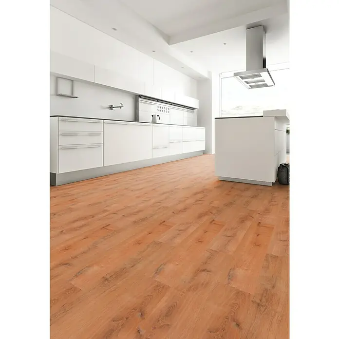 Star Clic Vinylboden More+ Golden Oak Natural1.210 x 220 x 5 mm, Landhausdiele, Golden Oak Natural - Blick auf eine moderne Küche mit hellbraunem Laminatboden, weißen Schränken und einer Dunstabzugshaube aus Edelstahl über einer Kochinsel.