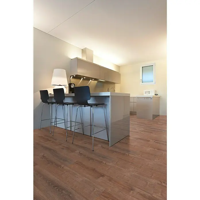 Star Clic Vinylboden More+ - Smoky Oak Natural, Landhausdiele, 1.210 x 220 x 5 mm - Ein modernes Küchendesign mit Holzboden und Barhockern vor einer Kücheninsel, ergänzt durch elegante Schränke und ein helles, einladendes Ambiente.