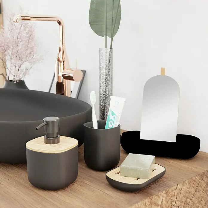 Venus Katta Seifenspender - Schwarz, Polyresin - Nahaufnahme eines Badezimmersets mit Seifenspender, Zahnbürstenhalter, Seife und Spiegel auf einem Holztisch.