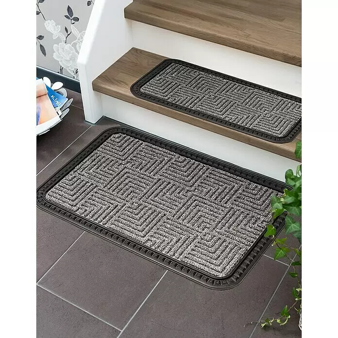 Astra Fußmatte Border Star - Silber, 40 x 60 cm, 70 % Polypropylen, 30 % Gummi - Zwei graue Matten mit geometrischem Muster und dunklem Rand, eine auf einer Holzstufe, eine auf Fliesenboden.