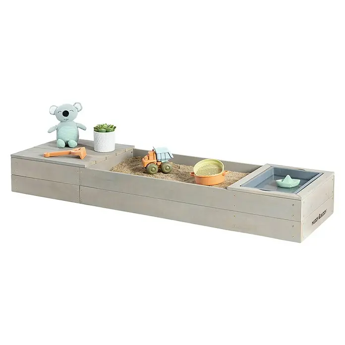 Muddy Buddy Sandkasten Space Saver - 150 x 45 x 20 cm, Holz, Warmgrau - Sandkasten aus Holz mit Spielzeug. Der Sandkasten enthält einen Bagger, einen Sieb, eine Pflanze, einen Koala und ein Papierboot im Wasserbecken.