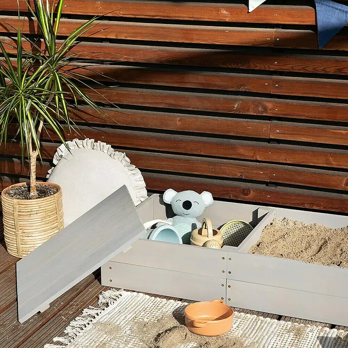 Muddy Buddy Sandkasten Space Saver - 150 x 45 x 20 cm, Holz, Warmgrau - Ein grauer Sandkasten mit Spielzeug und einem Plüschkoala, der zum Spielen im Freien einlädt.