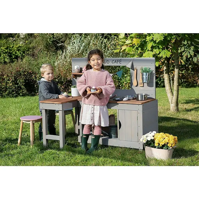 Muddy Buddy Matschküche Mud Café - 110 x 71,5 x 100 cm, Holz, Warmgrau - Ein grauer Spielküchen-Set für Kinder im Freien mit zwei Kindern, die damit spielen.