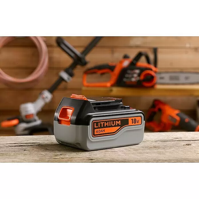Black+Decker Akku BL4018-XJ - 18 V, 4 Ah - Black & Decker 18V 4.0AH Lithium-Akku, grau/schwarz mit orangefarbenen Akzenten, auf Holzwerkbank mit verschwommenen Werkzeugen im Hintergrund.
