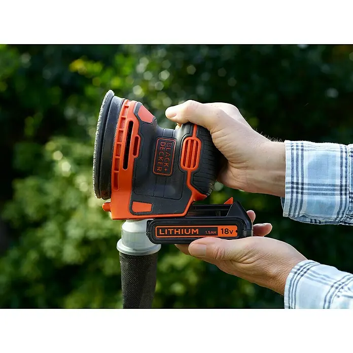 Black+Decker Akku-Exzenterschleifer BDCROS18-QW - 18 V, Li-Ionen, 1,5 Ah, 1 Akku, 125 mm - Nahaufnahme eines Black+Decker Exzenterschleifers in Aktion, der von einer Person im Freien gehalten wird.