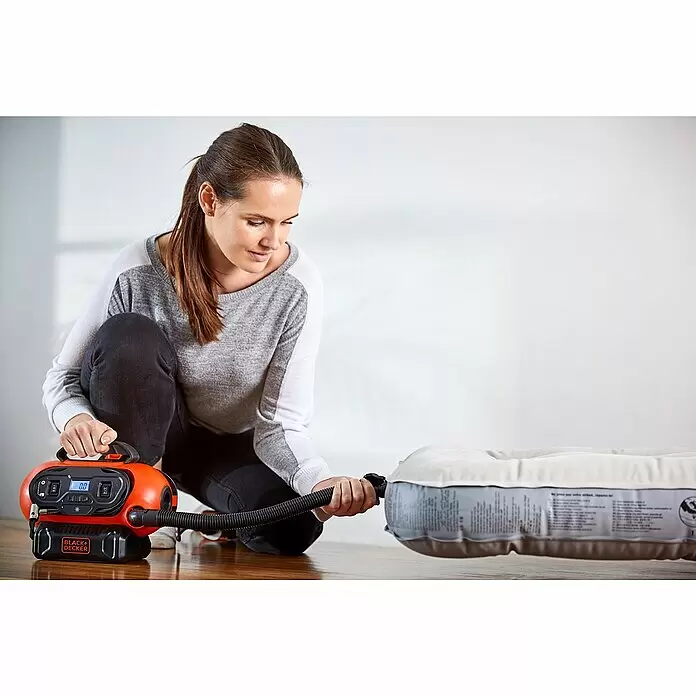 Black+Decker Akku-Kompressor BDCINF18N-QS - 18 V, Ohne Akku, 11 bar - Eine Frau bläst eine Luftmatratze mit einem orange-schwarzen Black+Decker Kompressor auf.