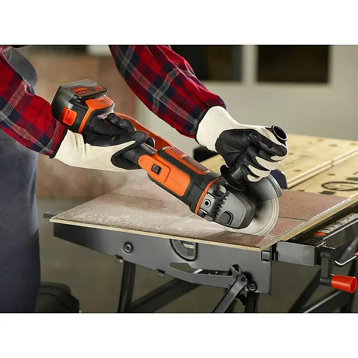 Black+Decker Akku-Winkelschleifer BCG720M1-QW - Li-Ionen, 4 Ah, 1 Akku, Durchmesser Scheibe: 125 mm, 8.600 U/min - Akkubetriebener Winkelschleifer von Black+Decker in Aktion, der auf einer Werkbank eine Fliese durchtrennt.