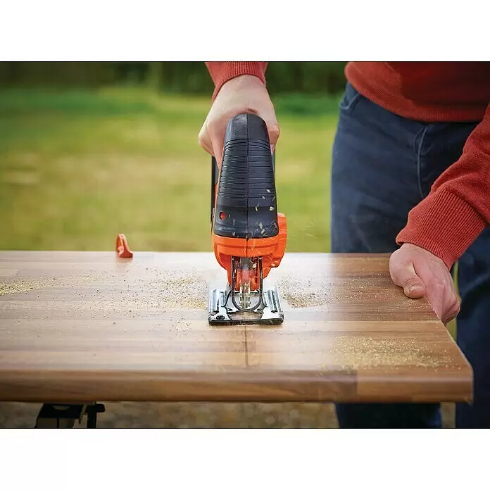 Black+Decker 18V PowerConnect Pendelhubstichsäge BDCJS18N-XJ - 18 V, Ohne Akku, 0 /min - 2.500 /min - Orange-schwarze Stichsäge schneidet eine Holzplatte, Sägemehl fliegt. Eine Person bedient das Werkzeug.