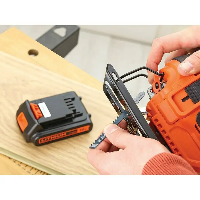Black+Decker 18V PowerConnect Pendelhubstichsäge BDCJS18N-XJ - 18 V, Ohne Akku, 0 /min - 2.500 /min - Nahaufnahme einer Stichsäge, in der eine Person ein Sägeblatt einsetzt, zusammen mit einem Akku für das Elektrowerkzeug auf einer Werkbank.