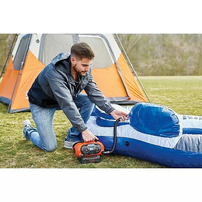 Black+Decker Akku-Kompressor BDCINF18N-QS - 18 V, Ohne Akku, 11 bar - Mann bläst eine blaue Luftmatratze mit einer orange-schwarzen tragbaren Luftpumpe neben einem Zelt auf.