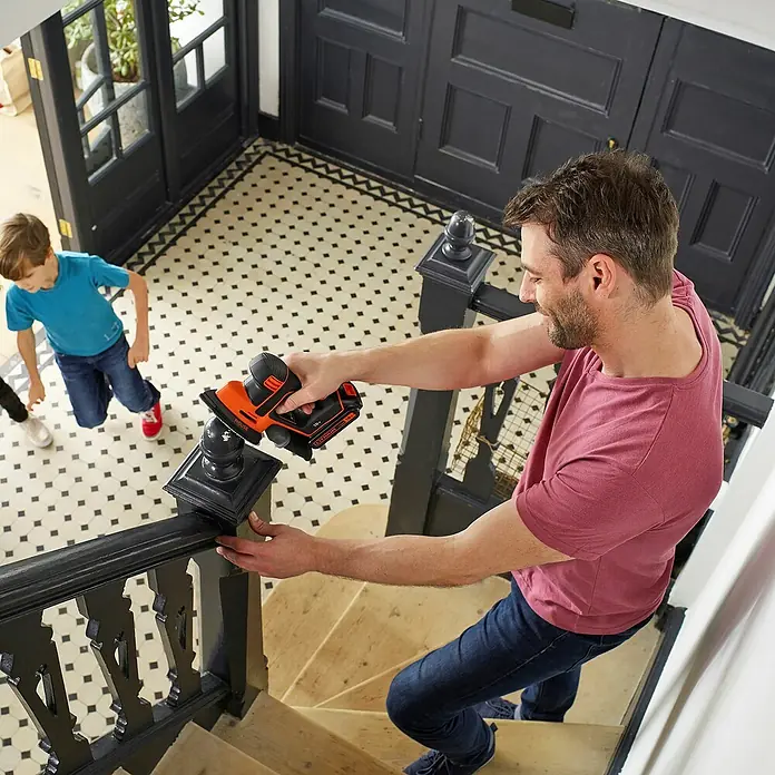 Black+Decker 18V PowerConnect Akku-Deltaschleifer Mouse® BDCDS18N-XJ - 18 V, Li-Ionen, Ohne Akku, 24.000 U/min - Ein Mann verwendet einen BLACK+DECKER Schleifer, um ein Holzgeländer zu schleifen, während ein Kind zusieht.