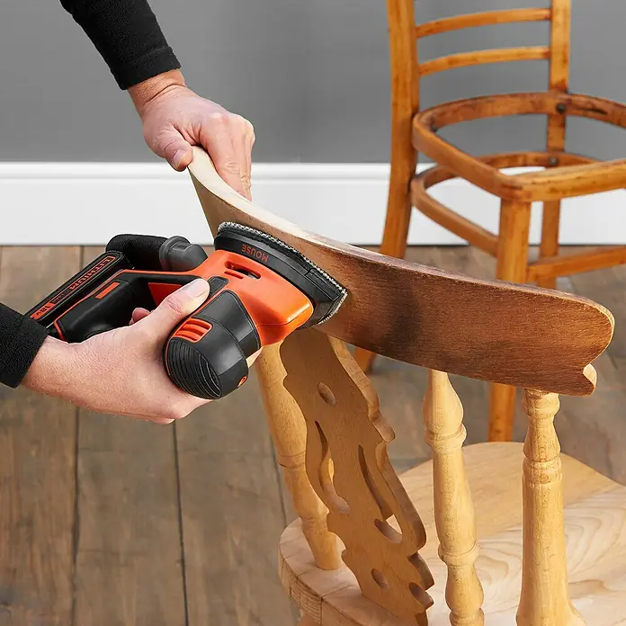 Black+Decker 18V PowerConnect Akku-Deltaschleifer Mouse® BDCDS18N-XJ - 18 V, Li-Ionen, Ohne Akku, 24.000 U/min - Detailaufnahme des Black+Decker Mouse-Schleifers beim Abschleifen eines Stuhls, ideal für präzise Holzarbeiten.