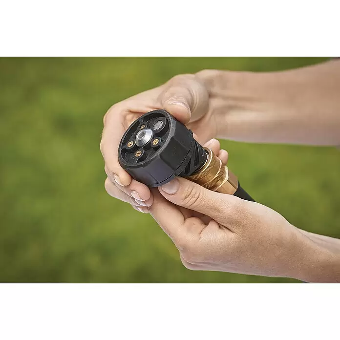 Black+Decker Akku-Druckreiniger BCPC18B - 18 V, Ohne Akku, 120 l/h - Nahaufnahme von Händen, die eine schwarze Schlauchdüse mit Messing-Schnellkupplung halten und den verstellbaren Sprühkopf zeigen.