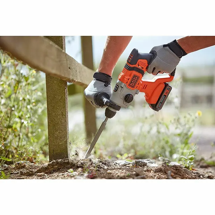 Black+Decker Akku-Kombihammer BCD900B-XJ - 18 V, Ohne Akku, 1,2 J - Ein Mann benutzt einen Black+Decker Akku-Bohrhammer, um einen Zaunpfosten zu befestigen. Der Bohrhammer ist orange und schwarz und hat einen grauen Griff.