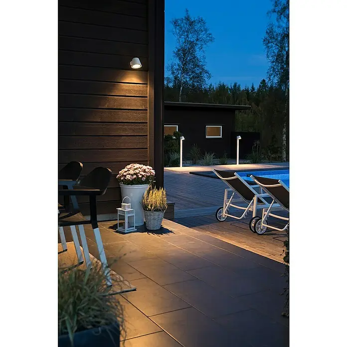 Konstsmide Außenwandleuchte - 35 W, 16 x 11,5 x 11 cm, Weiß, IP44 - Eine Außenansicht mit dekorativer Beleuchtung, die eine gemütliche Atmosphäre auf der Terrasse mit Pool schafft. Die Leuchten setzen elegante Akzente.