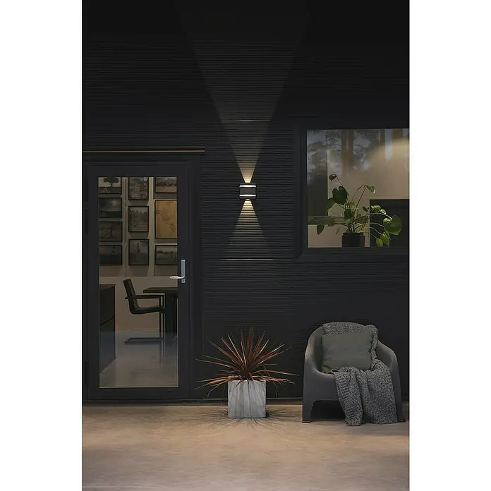 Konstsmide LED-Außenwandleuchte - 7,2 W, 4 x 18,5 x 9,5 cm, Weiß, IP54 - Außenansicht eines Hauses mit einer modernen Wandleuchte, die Licht nach oben und unten abstrahlt und eine gemütliche Atmosphäre schafft.