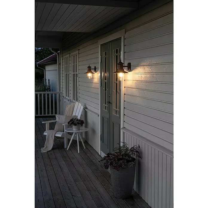 Konstsmide LED-Außenwandleuchte - 7,2 W, 4 x 18,5 x 9,5 cm, Anthrazit, IP44 - Zwei rustikale Wandleuchten aus Metall beleuchten eine gemütliche Veranda mit Holzboden und weißer Holzverkleidung.