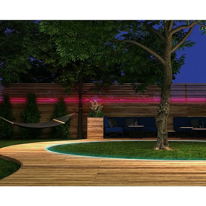 Müller-Licht Tint Smart-LED-Band Outdoor - Weiß, 5 m, RGBW - Bild eines modernen Gartens mit Holzterrasse, Rasenfläche, blauen Sofas und stimmungsvoller Beleuchtung. Ideal für Entspannung im Freien.